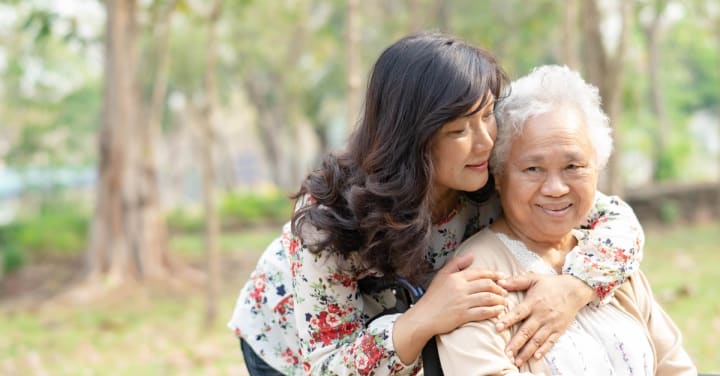 Dementia Care: Decode Your Genetic Risk &Amp; Protect Your Family 1 A Younger Woman Gently Embraces An Older Woman From Behind As They Pose Together Outdoors.
